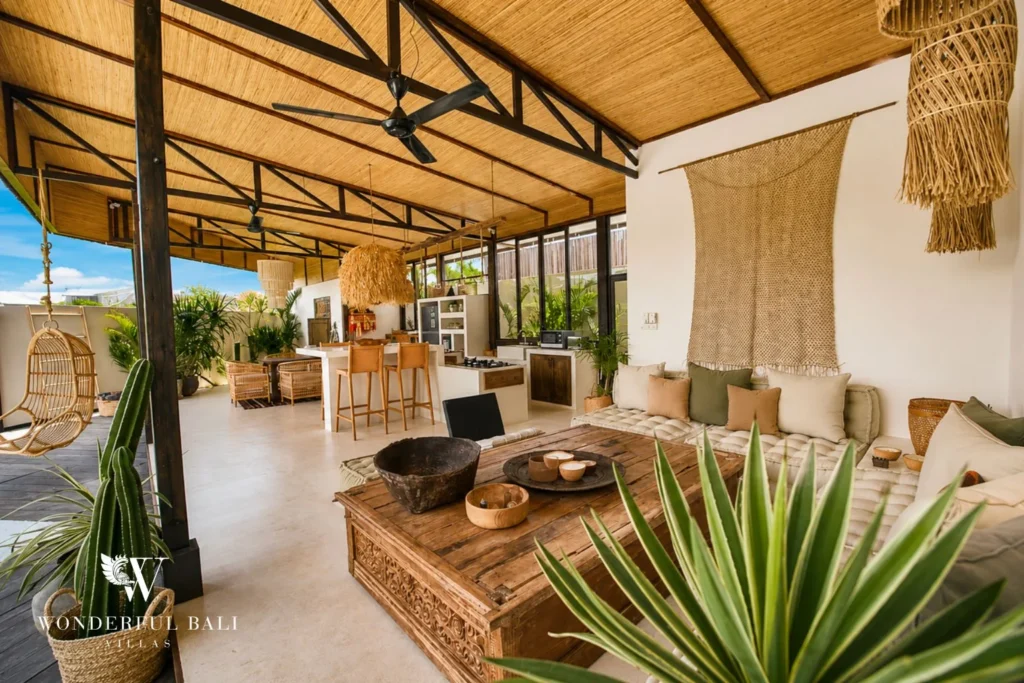 Open-plan living and kitchen under black steel trusses and a bamboo ceiling in Umalas Bali