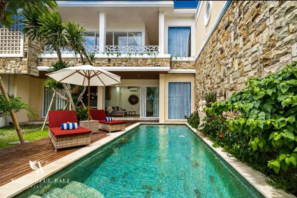 Green mosaic pool below the stone facade at a 3-bedroom villa in Tumbak Bayuh Bali