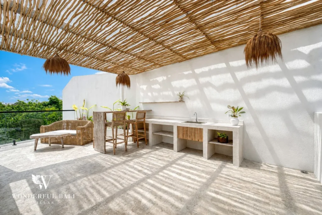 Rooftop outdoor kitchen with stone counter and sink under an alang-alang pergola near Nusa Dua Bali