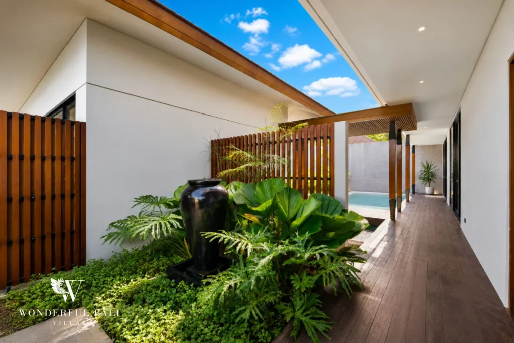 Hardwood entrance walkway past a planted courtyard and water jar at a 3-bedroom villa in Jimbaran Bali