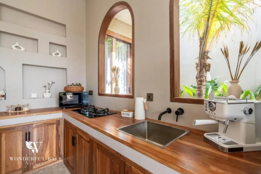 Teak worktop with sink, hob and coffee machine under an arched window in Pererenan Bali