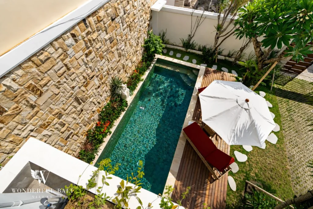 Green mosaic pool and teak deck seen from the balcony at a 3-bedroom villa in Tumbak Bayuh Bali