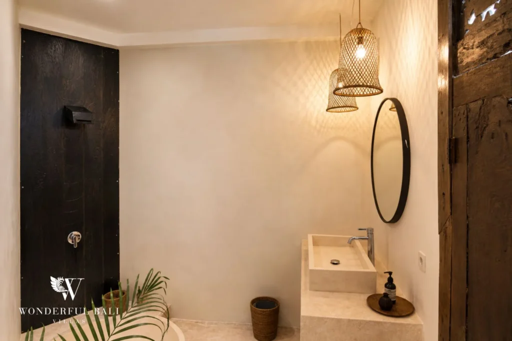 Bathroom with a carved stone basin and round mirror in a 3-bedroom villa in Umalas Bali
