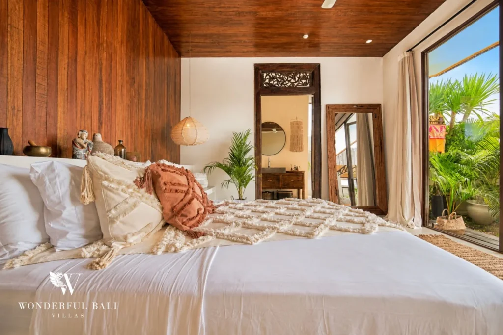 Bedroom with a timber panel wall, carved mirror and rattan pendant in Umalas Bali