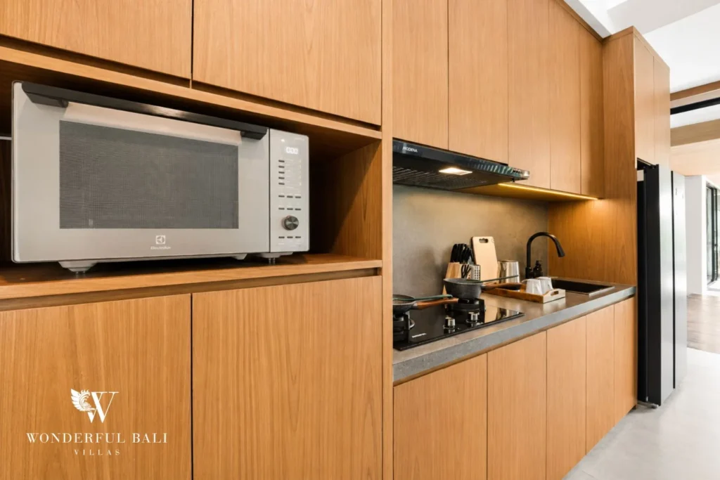 Kitchen worktop with microwave and oak cabinetry in a 3-bedroom villa in Jimbaran Bali