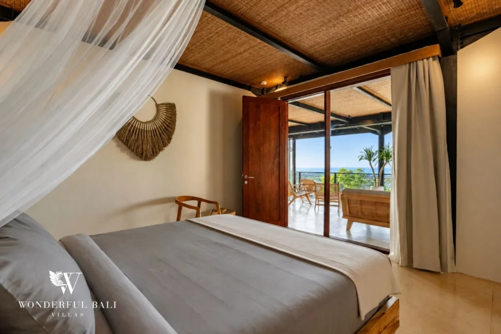 Bedroom with draped mosquito net opening to an ocean-facing balcony in a 5-bedroom villa in Uluwatu Bali