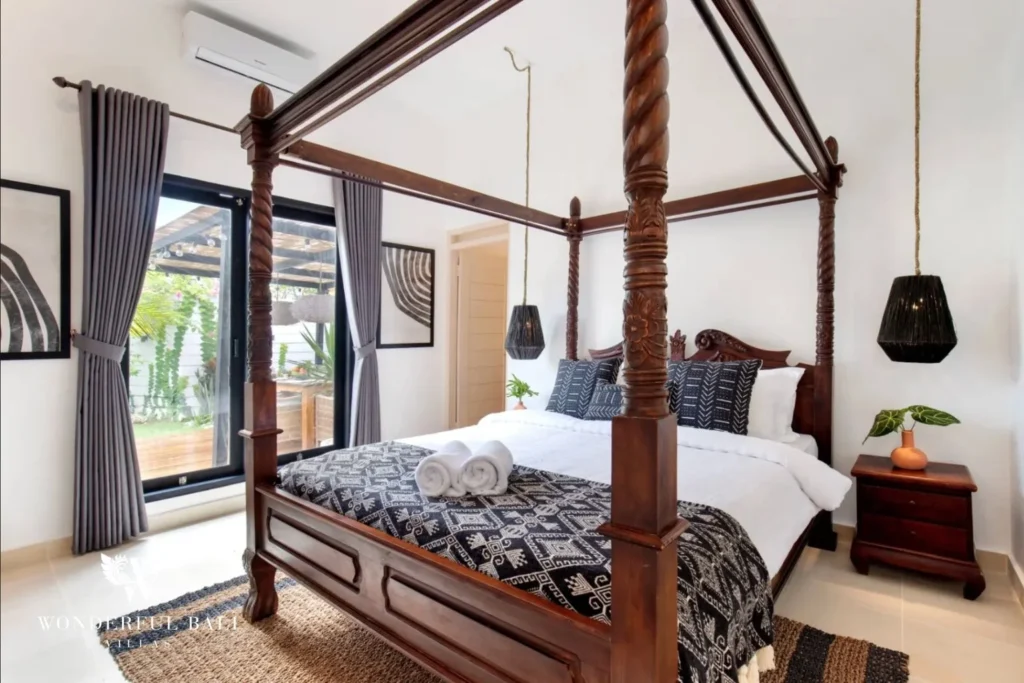 Bedroom with carved teak four-poster bed in a 3-bedroom villa in Umalas Bali