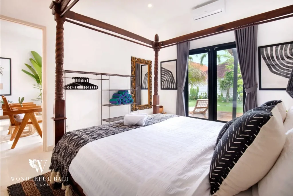 Four-poster bedroom with open wardrobe and garden doors in a 3-bedroom villa in Umalas Bali