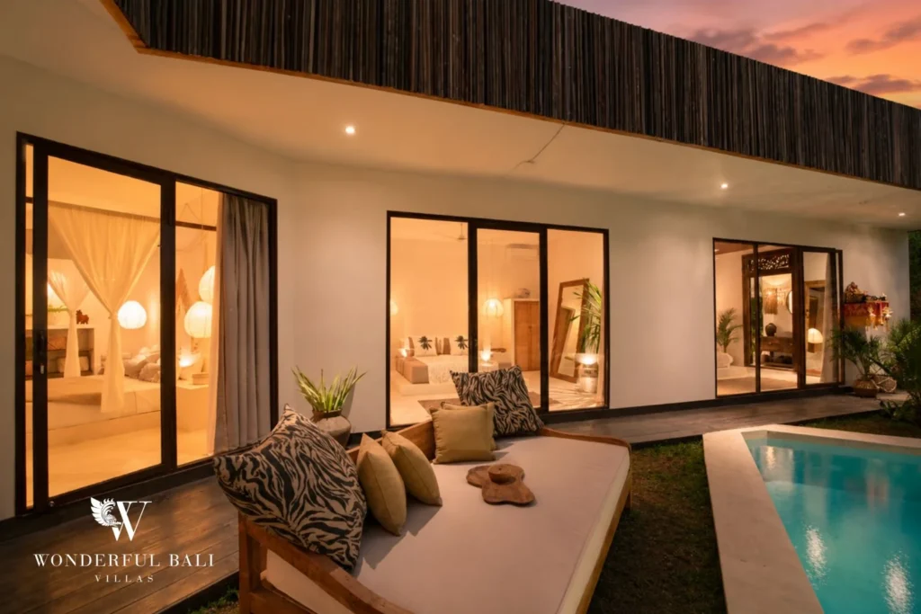 Pool and lit bedrooms at dusk at a 3-bedroom villa in Umalas Bali