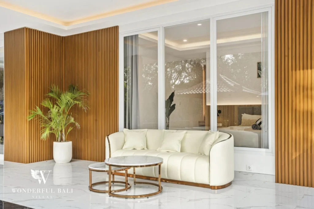 Seating room with fluted timber walls and curved cream sofa in a 3-bedroom villa in Kaba-Kaba Bali