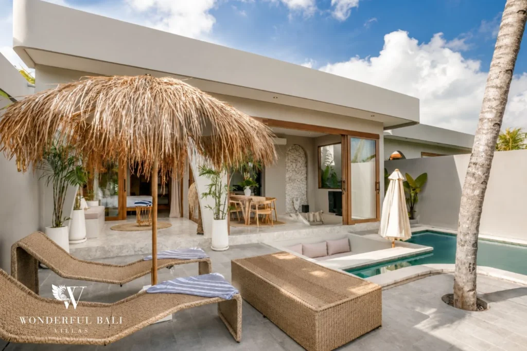 Rattan lounge and thatched parasol beside the pool at a 2-bedroom villa in Pererenan Bali