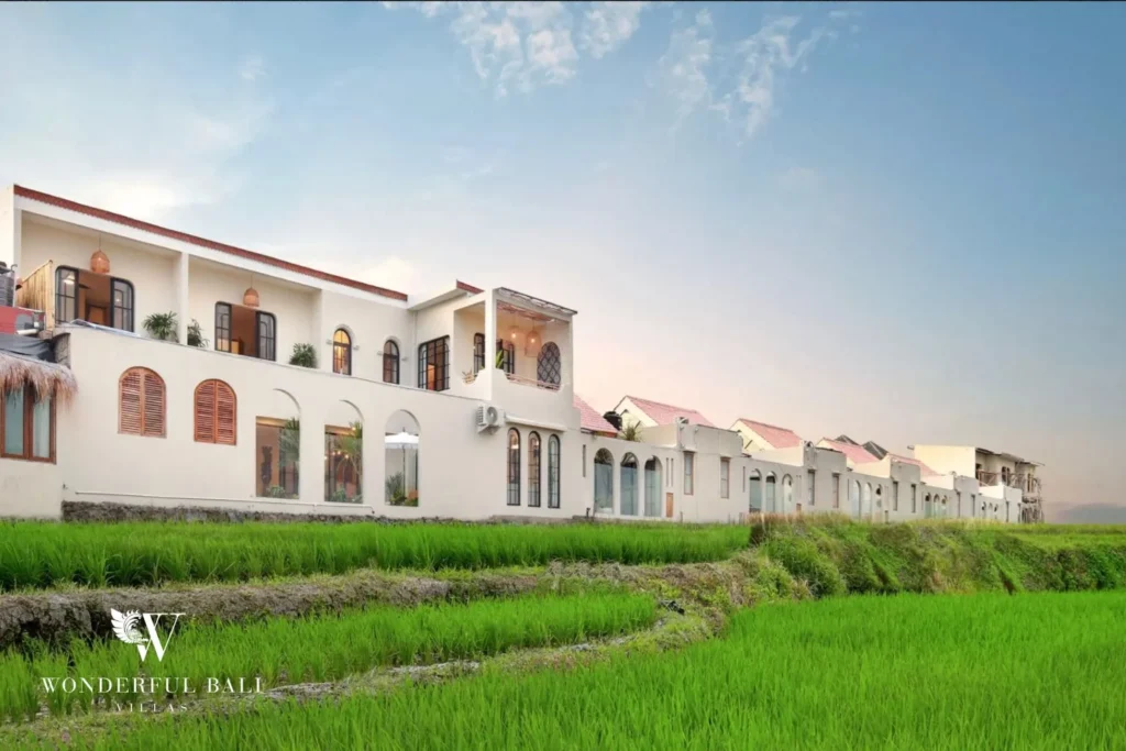 White arched villas seen across open rice fields in Buduk Canggu Bali