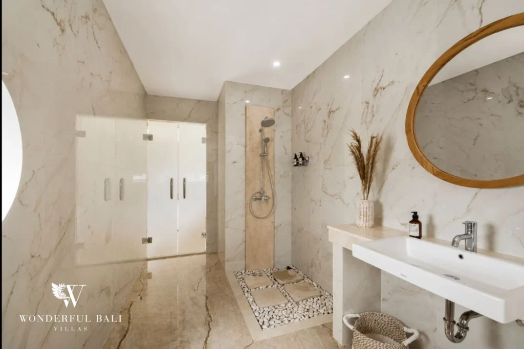 Marble bathroom with pebble-floored walk-in shower in a 3-bedroom villa in Tumbak Bayuh Bali