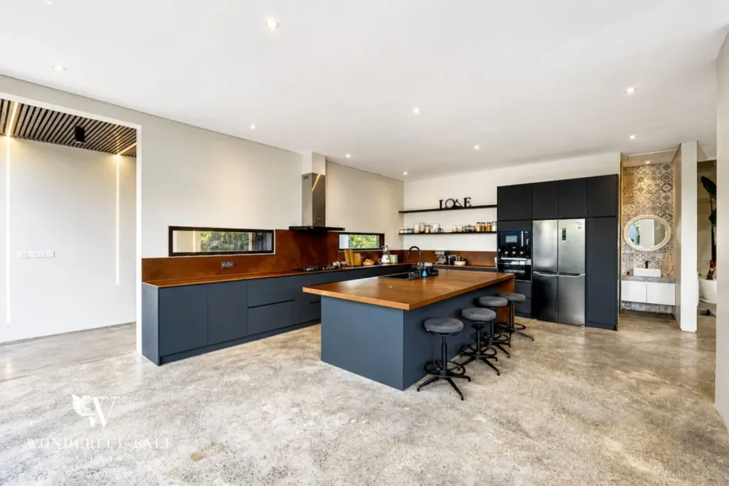 4BR villa for rent in Seminyak — kitchen, dark cabinetry and a timber-topped island with bar seating
