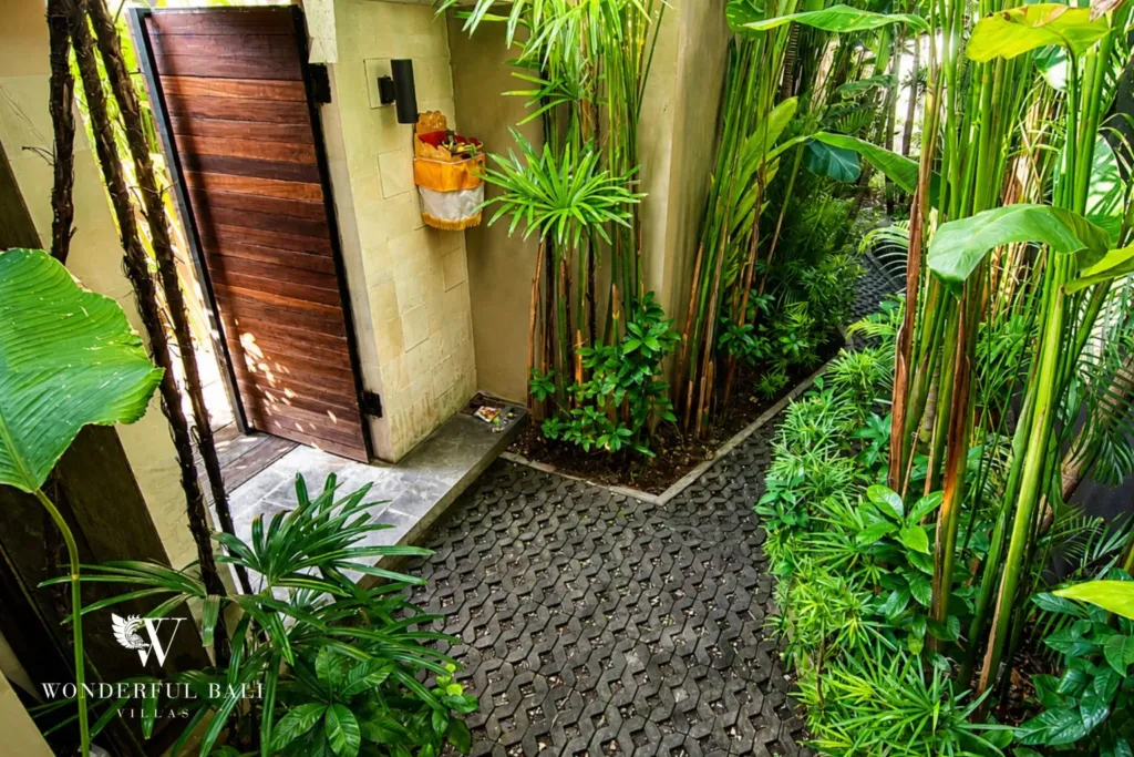 2BR villa for rent in Bumbak, Umalas — entrance, timber entrance gate and paver path through dense tropical planting at a 2-bedroom villa
