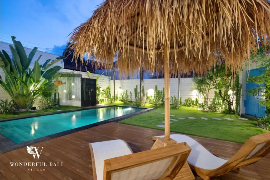 Sun loungers and thatched parasol beside the pool at dusk at a 3-bedroom villa in Umalas Bali