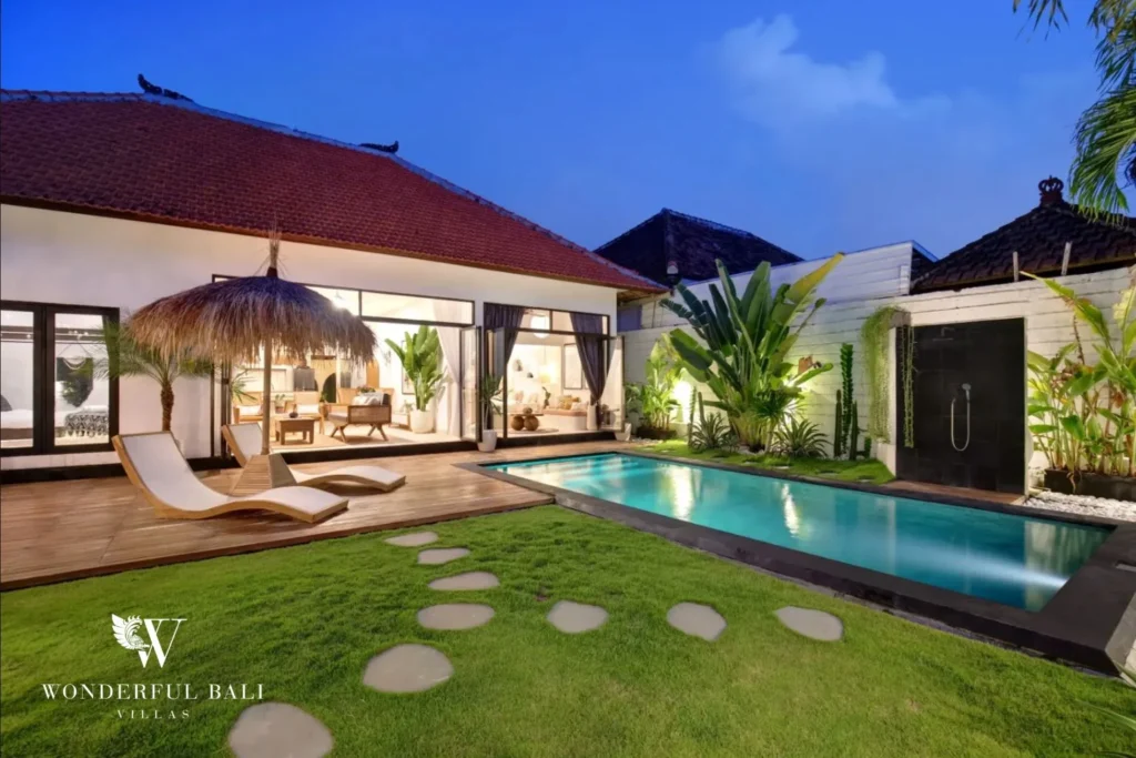 Lawn stepping stones and lit pool at dusk at a 3-bedroom villa in Umalas Bali