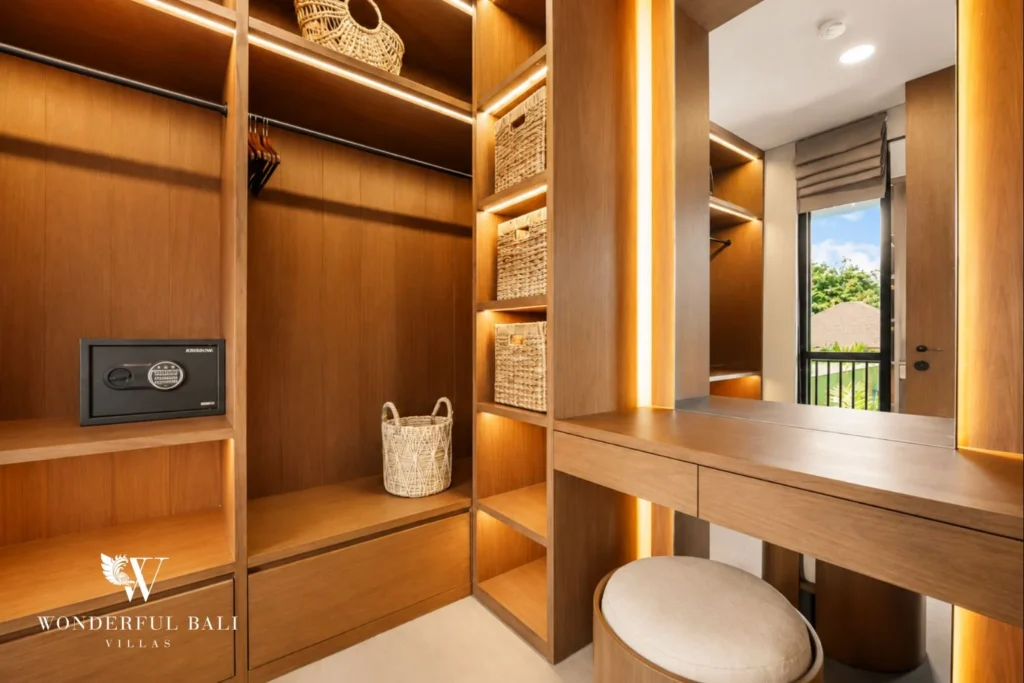 Walk-in wardrobe with backlit oak shelving and a safe in a 3-bedroom villa in Jimbaran Bali