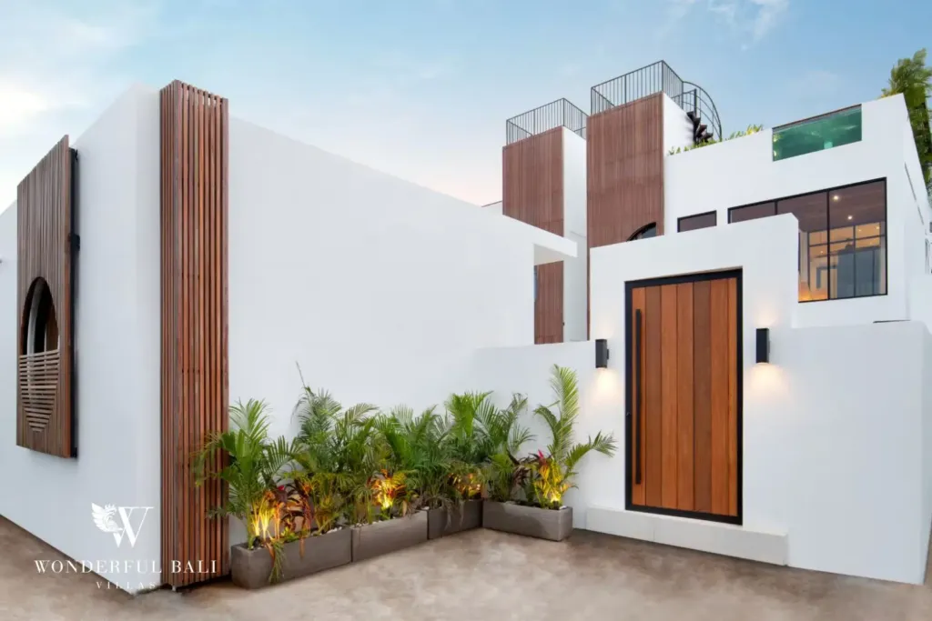 Villa entrance with timber door and planted courtyard at dusk at a 3BR villa in Pererenan Bali
