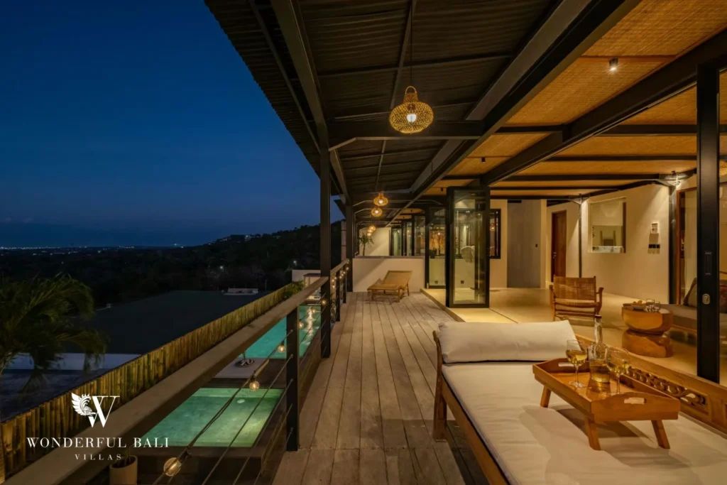 Upper timber deck with festoon lights above the pool at dusk in Uluwatu Bali