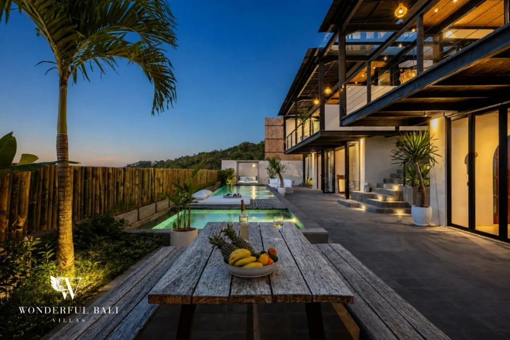 Villa and pool lit at dusk with a teak picnic table in Uluwatu Bali