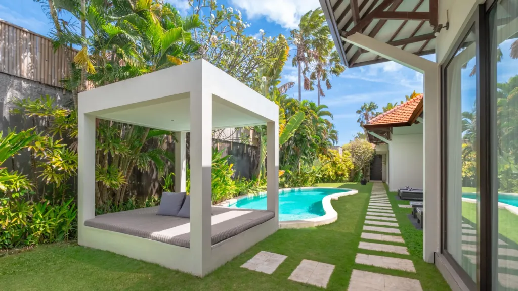 White pergola shading a daybed by the pool at Villa Alice Satu