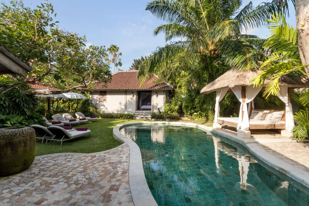 Villa Koyama's curved pool edged with sun loungers and palms