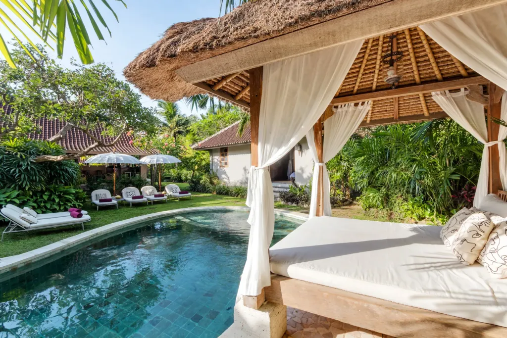 Thatched bale with daybed and curtains at the edge of Villa Koyama's pool