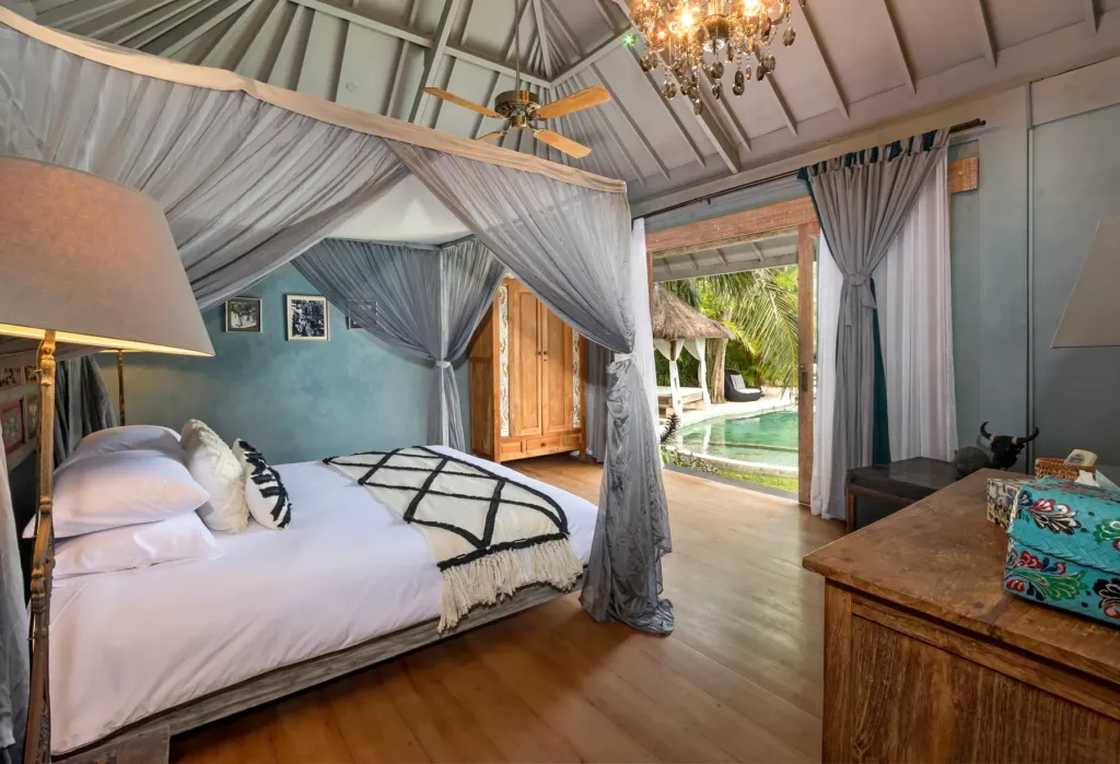 Canopy king bed at Villa Koyama with doors opening toward the pool