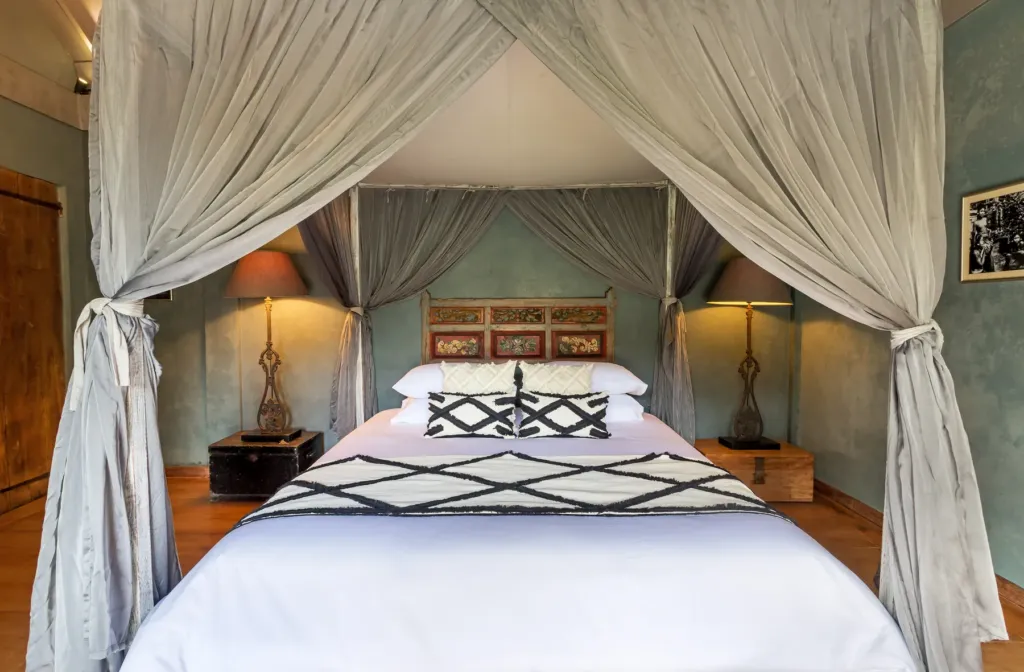 Four-poster king bed and carved headboard in a bedroom at Villa Koyama