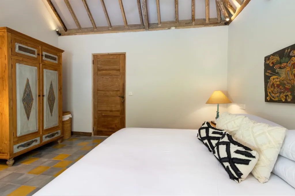 Bedroom at Villa Koyama with carved wardrobe and tiled floor