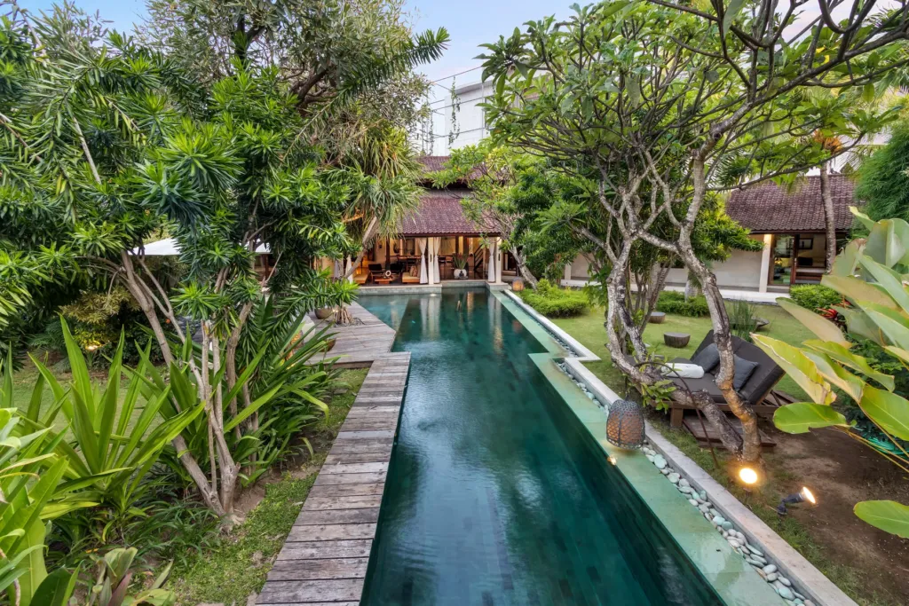 Long lap pool at Villa Shantika framed by mature pandanus and frangipani