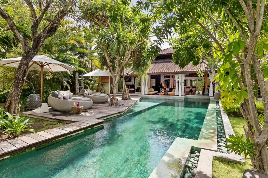 Parasols and daybeds along the pool at Villa Shantika, central Seminyak