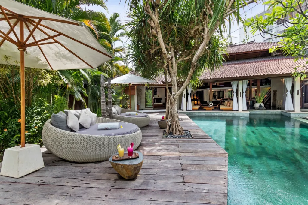 Cushioned round daybed under a parasol at the edge of Villa Shantika's pool