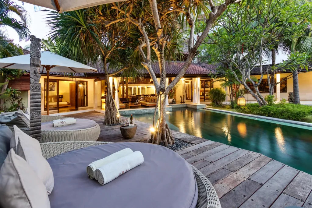 Poolside daybed at Villa Shantika with the pavilions lit behind