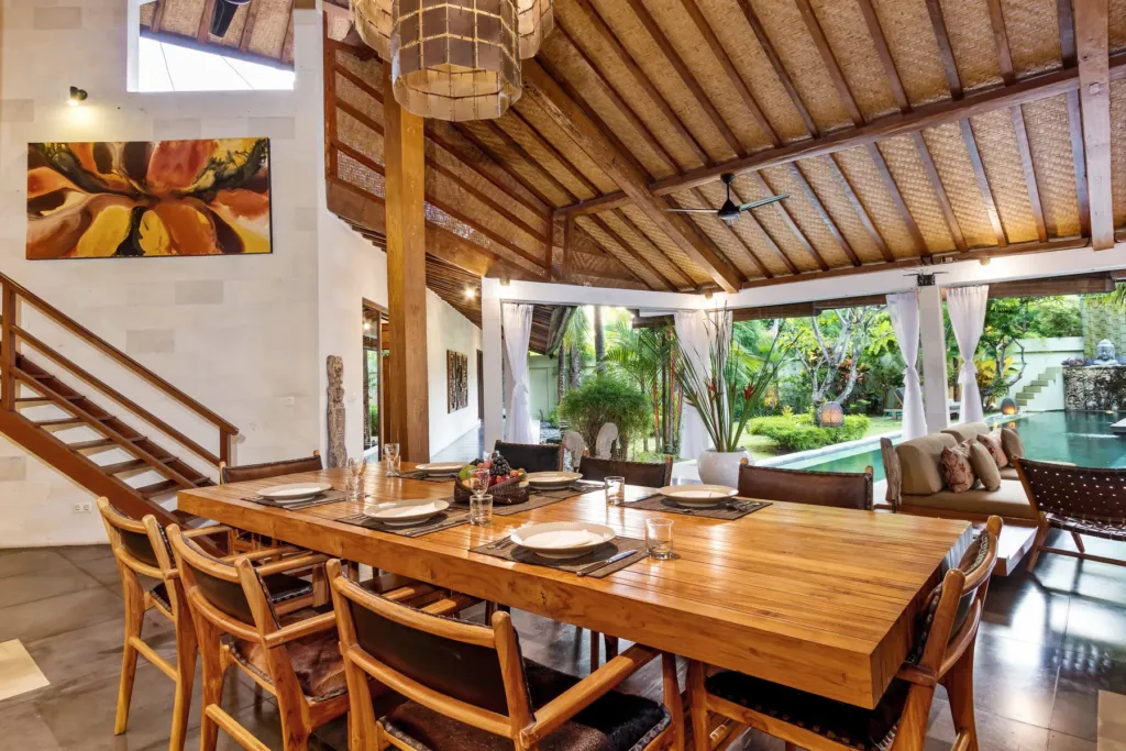 Dining table set for a meal at Villa Shantika, pool beyond