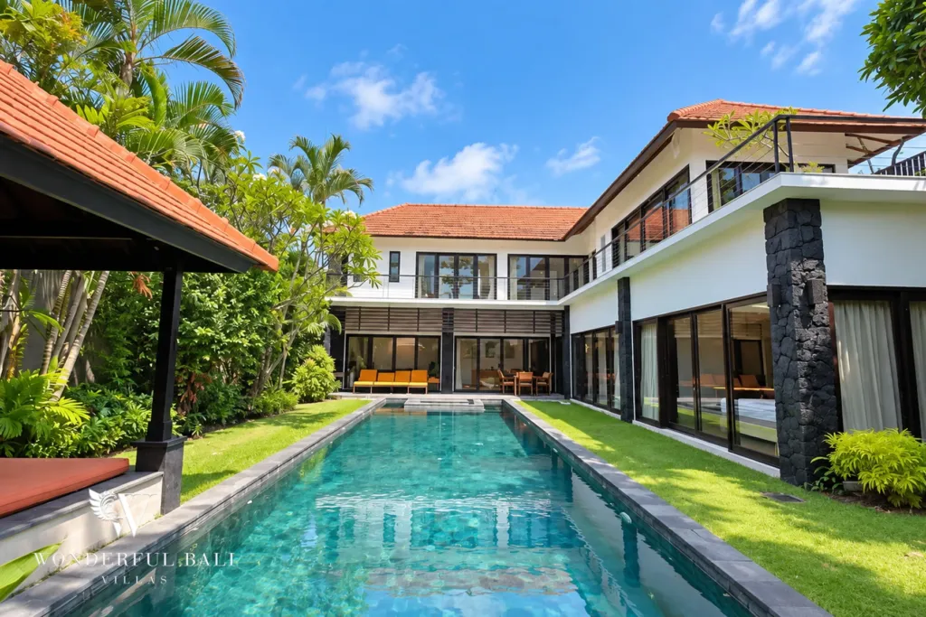 4BR villa for rent in Umalas, Bali — exterior, two-storey villa along a long lap pool with lawn and a thatched bale