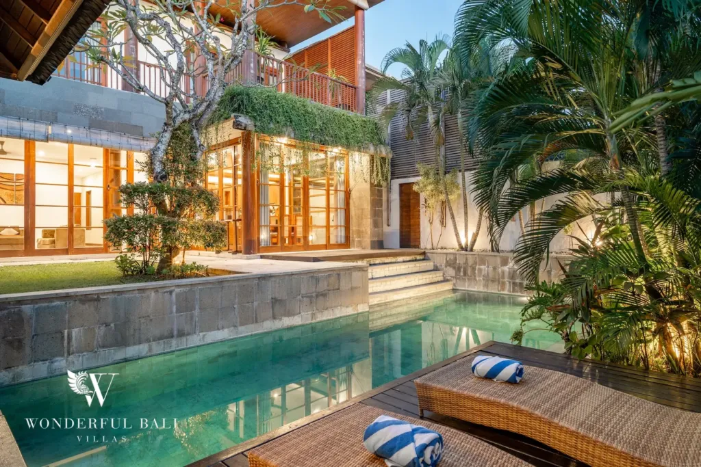 3BR villa for rent in Batu Belig, Seminyak — pool, private lap pool and timber deck below the lit two-storey villa