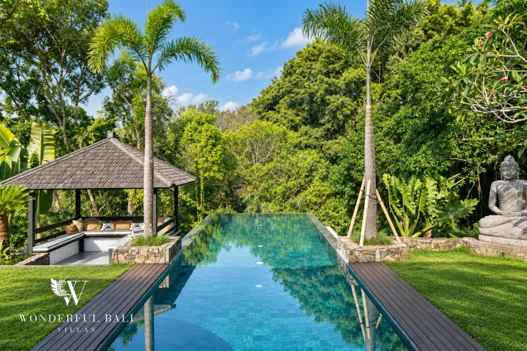 5BR villa for rent in Munggu, Bali — pool, long infinity pool with a thatched garden gazebo and jungle behind