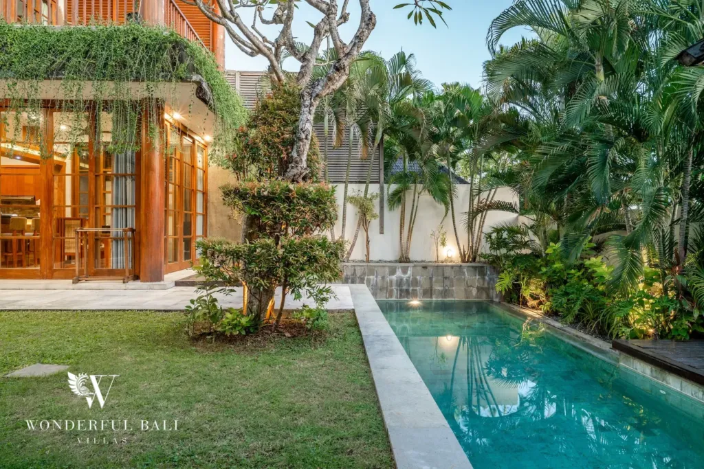 3BR villa for rent in Batu Belig, Seminyak — pool, lap pool along the lawn with frangipani trees and a stone garden wall
