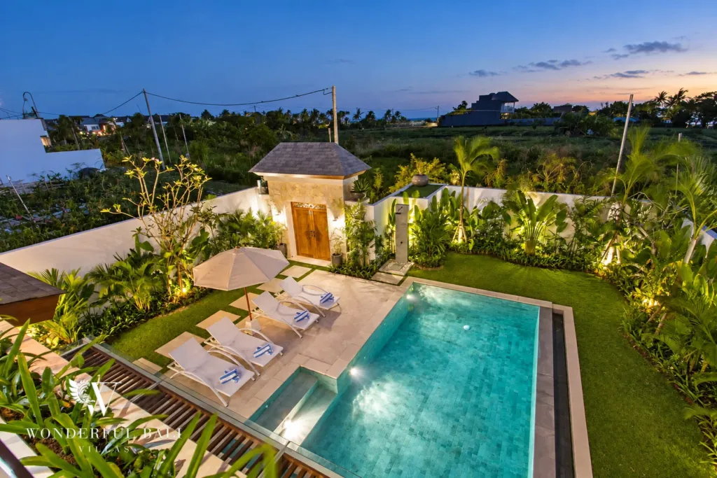 4BR villa for rent in Cemagi — pool, pool, sun loungers and garden with rice fields beyond at dusk