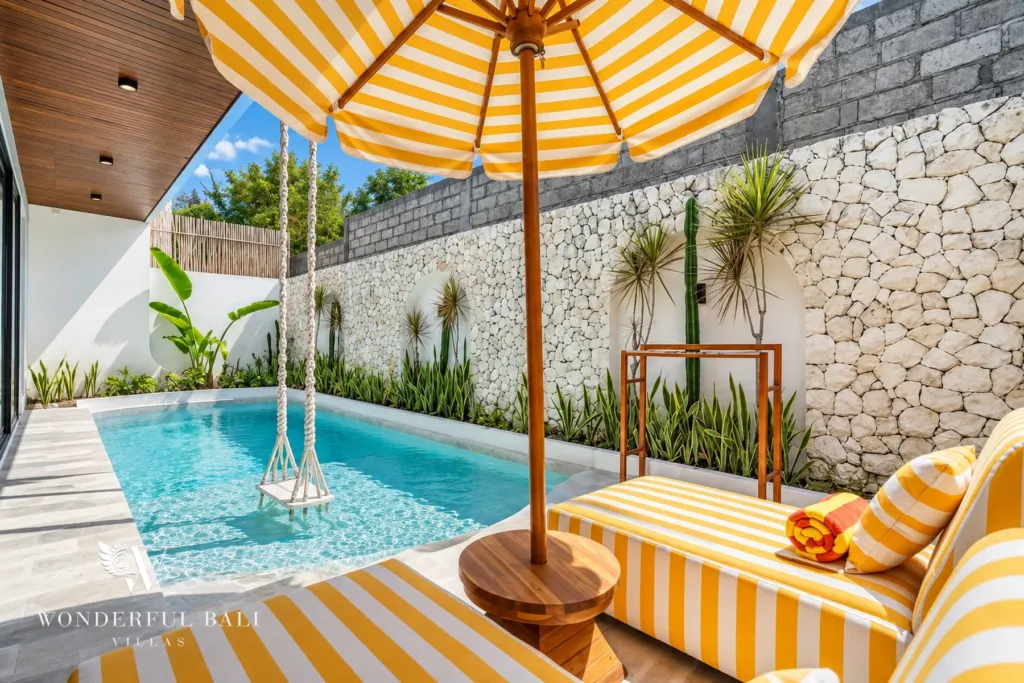 3BR villa for rent in Umalas, Bali — pool, striped parasol and daybed on the terrace beside the pool