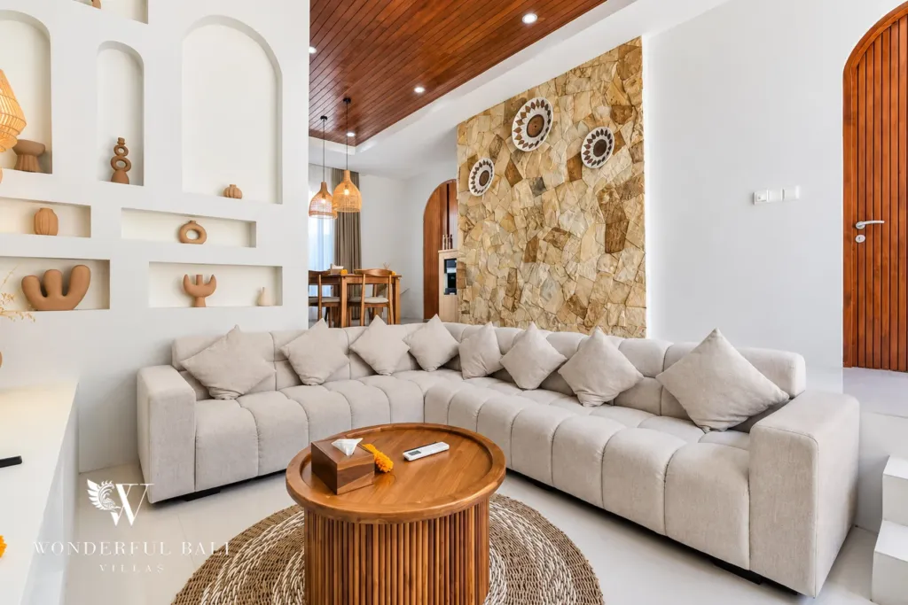 3BR villa for rent in Umalas, Bali — living room, curved sofa and stone feature wall under a timber slat ceiling
