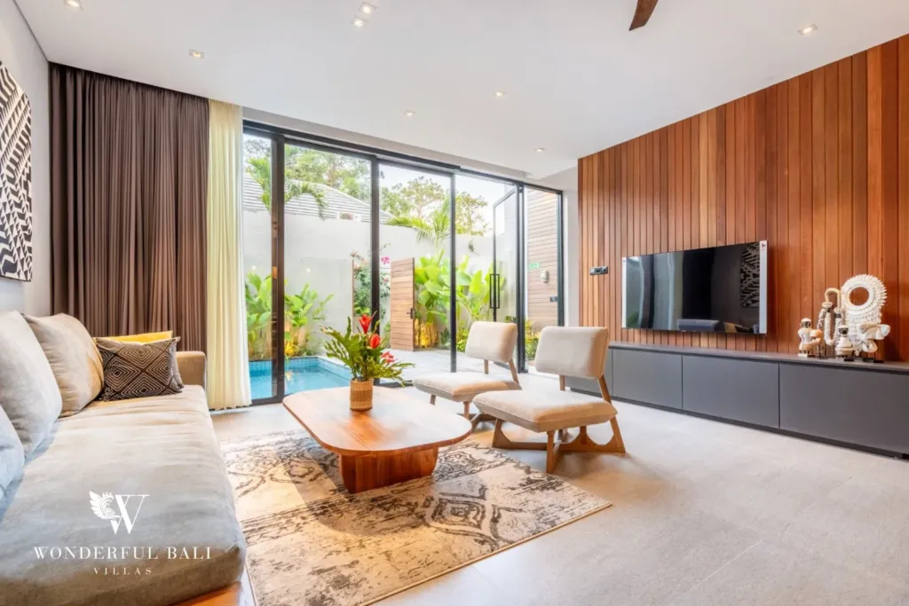 3BR villa for rent in Seminyak — living room, sofa and smart TV facing the pool through full-height glass