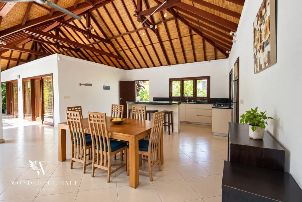 3BR villa for rent in Padonan, Canggu — dining area, teak dining table with the open kitchen along the far wall