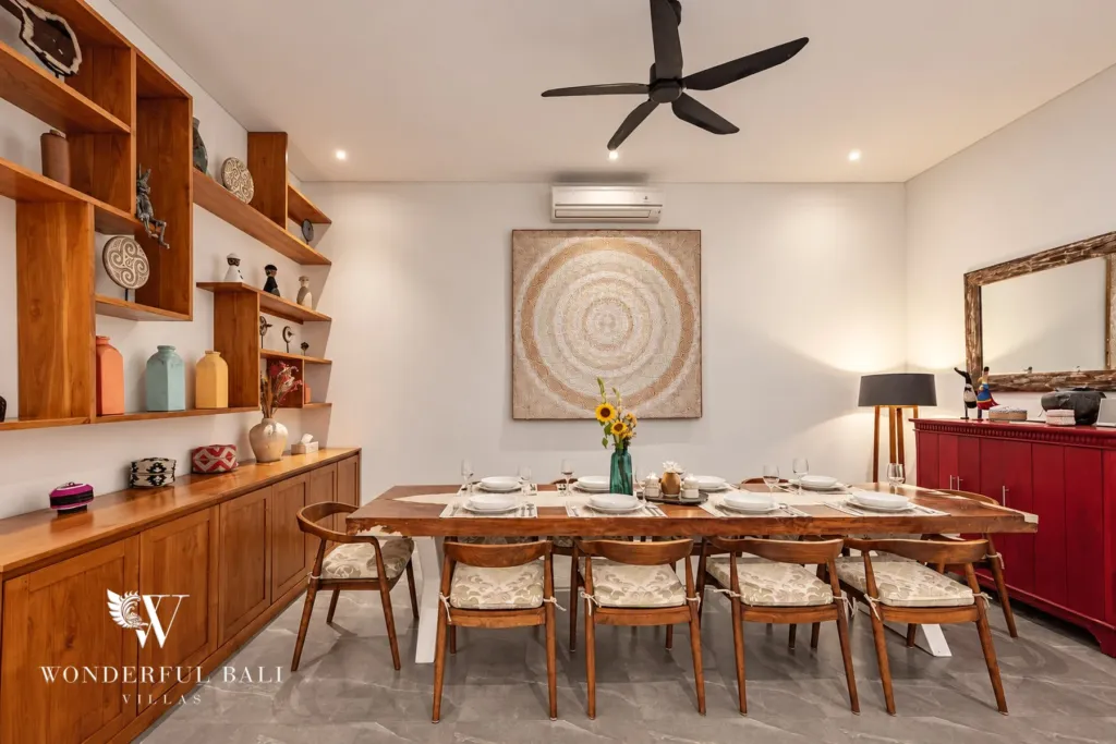 5BR villa for rent in Bumbak, Umalas — dining room, long teak dining table below a woven wall panel and open shelving