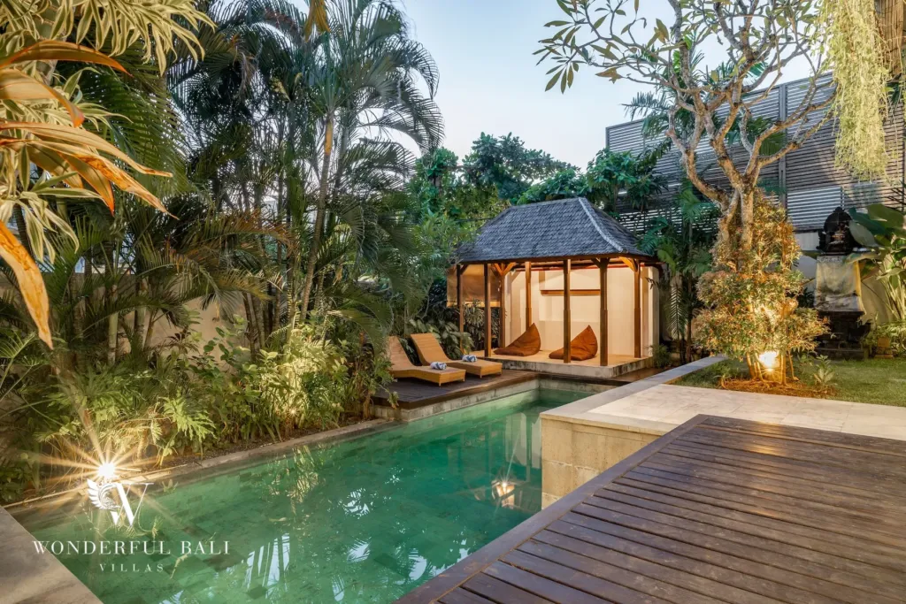 3BR villa for rent in Batu Belig, Seminyak — garden, thatched garden gazebo and sun loungers beside the pool at dusk