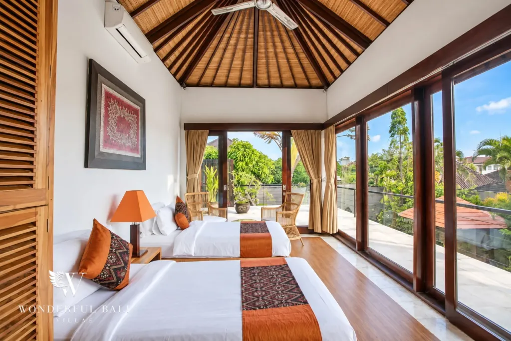 4BR villa for rent in Umalas, Bali — bedroom, twin beds under a vaulted alang-alang roof with doors onto the upstairs veranda