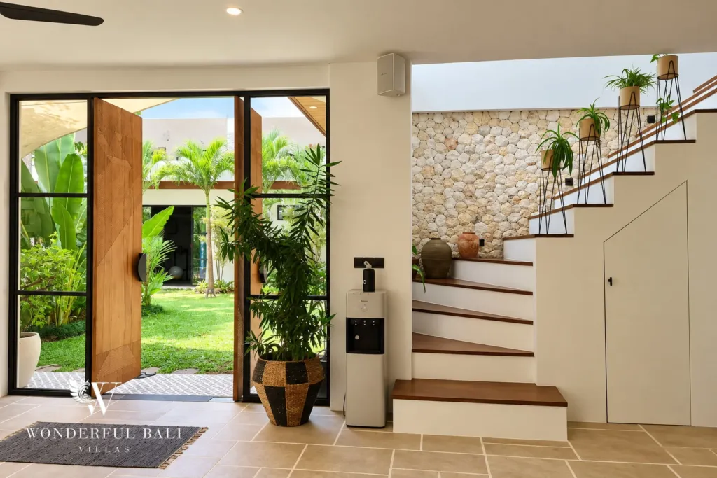 5BR villa for rent in Seseh, Bali — entrance, pivot door onto the garden with the stair and a stone-clad wall