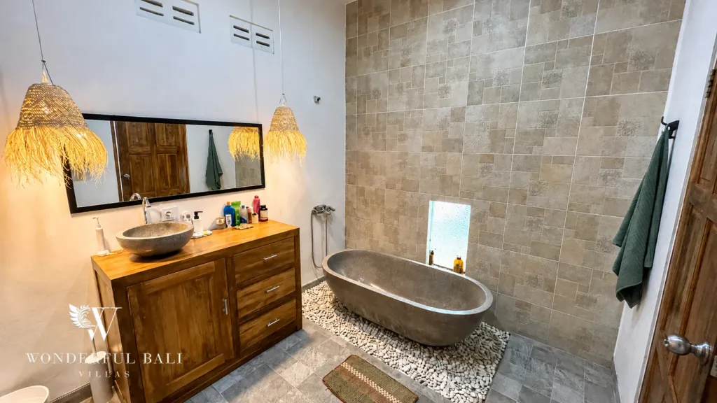 3BR villa for rent in Umalas — bathroom 1, stone soaking tub on a pebble floor beside a timber vanity